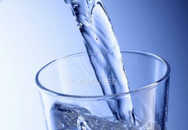 Verter agua en el vaso - foto de stock