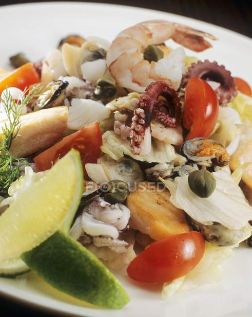 Closeup view of seafood salad with lime wedges — Stock Photo