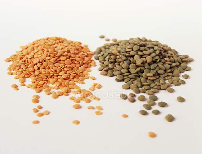 Closeup view of red and green lentils on white surface — Stock Photo