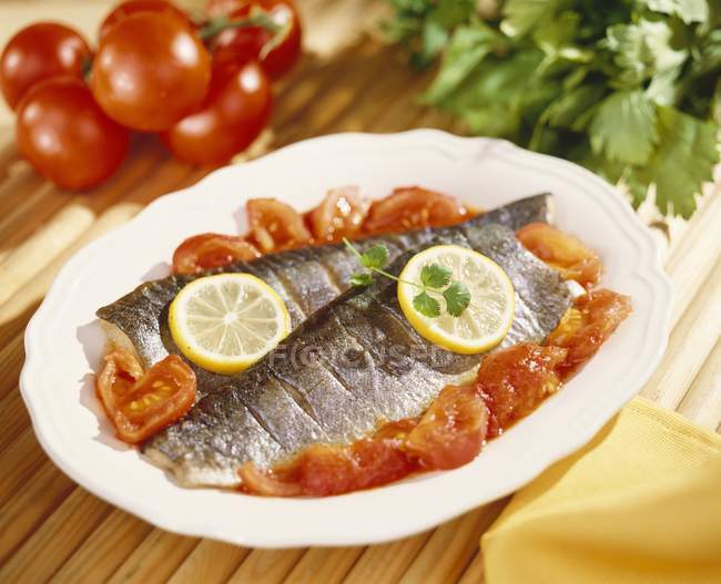 Closeup view of steamed trouts with tomatoes and lemons — Stock Photo