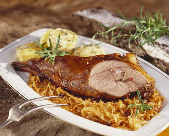 Roast leg of wild boar with sauerkraut and dumplings on white plate — Stock Photo