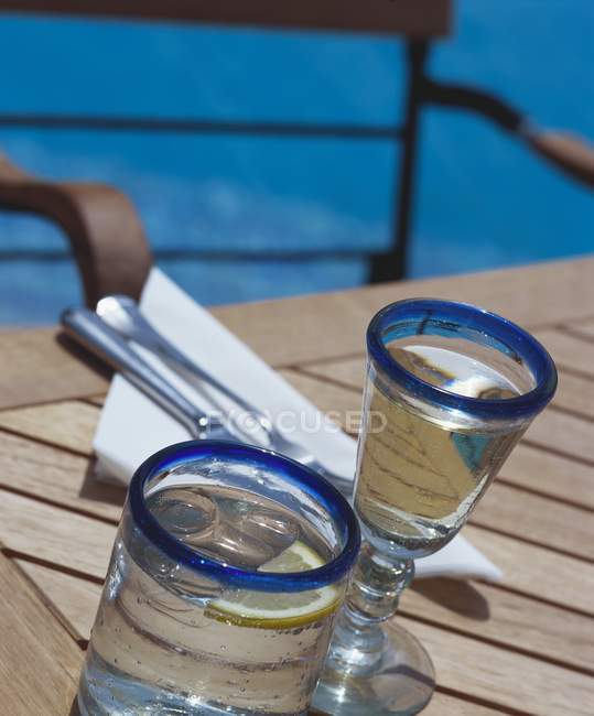 Vista de cerca de dos vasos de agua con cubos de limón y hielo - foto de stock