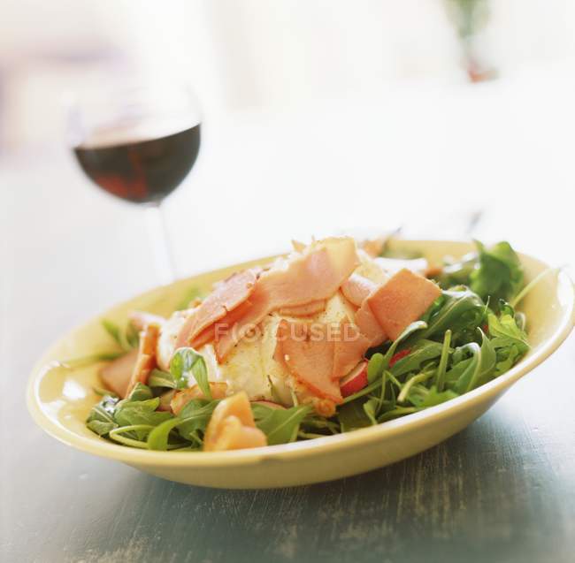 Rocket salad with mozzarella and ham on yellow plate over table — Stock Photo
