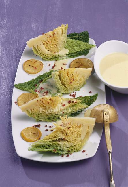 Savoy cabbage with lemon sauce and red pepper  on white plate over purple surface — Stock Photo