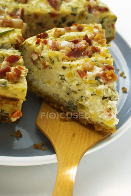 Leek and bacon quiche, a piece cut, with piece on server — Stock Photo