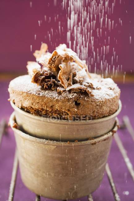 Closeup view of sprinkling icing sugar on chocolate souffle — Stock Photo