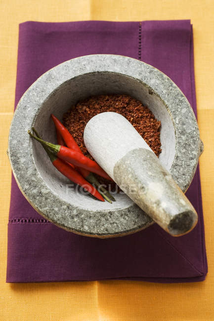 Chili peppers and powder in mortar — Stock Photo