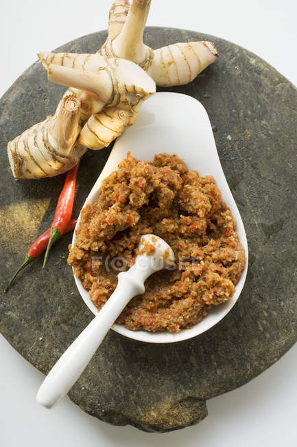 Chili paste with galanga on white plate with mortar — Stock Photo