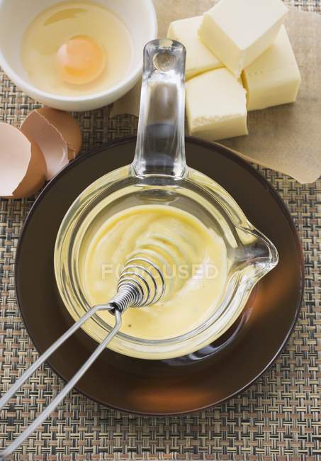 Elevated view of Hollandaise sauce with a whisk in glass bowl — Stock Photo