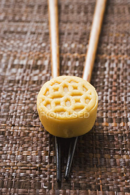 Closeup view of marzipan and white chocolate Asian candy on chopsticks — Stock Photo