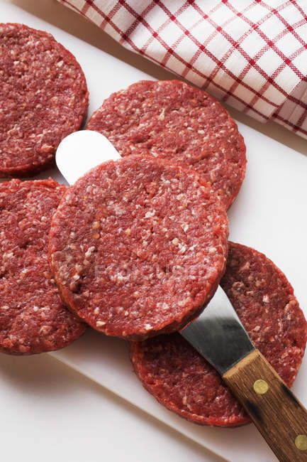 Raw burgers on chopping board — Stock Photo
