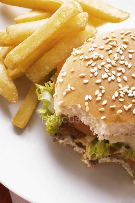 Bitten Cheeseburger with chips — Stock Photo