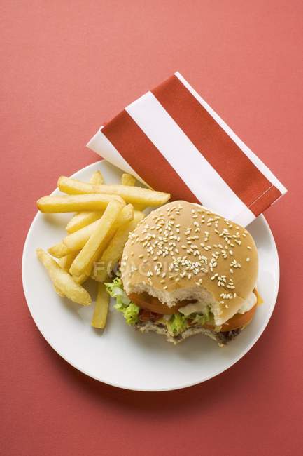 Cheeseburger mordido com batatas fritas — Fotografia de Stock