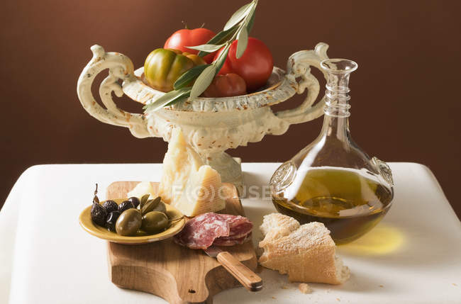 Vista de cerca de aceitunas con salchichas, parmesano, aceite, pan blanco y tomates - foto de stock