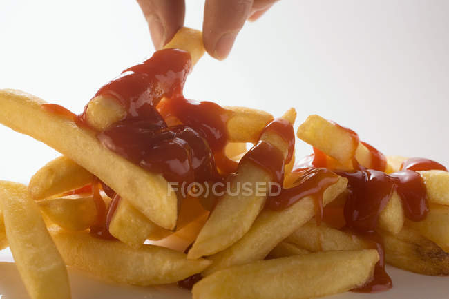 Hand taking french potato fries — Stock Photo
