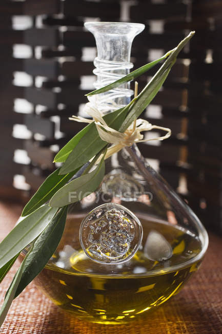 Крупним планом оливкова олія в карафе з оливковою гілкою — стокове фото