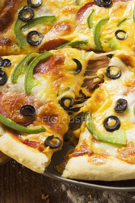 Pizza con queso, salami y pimientos - foto de stock