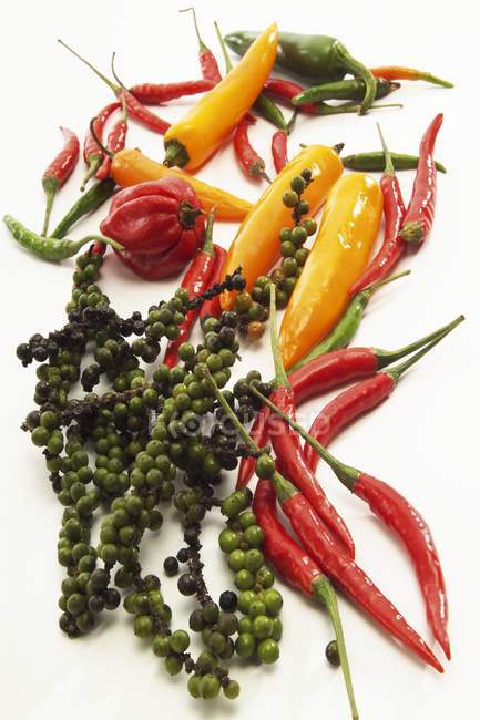 Green peppercorns and chili peppers — Stock Photo