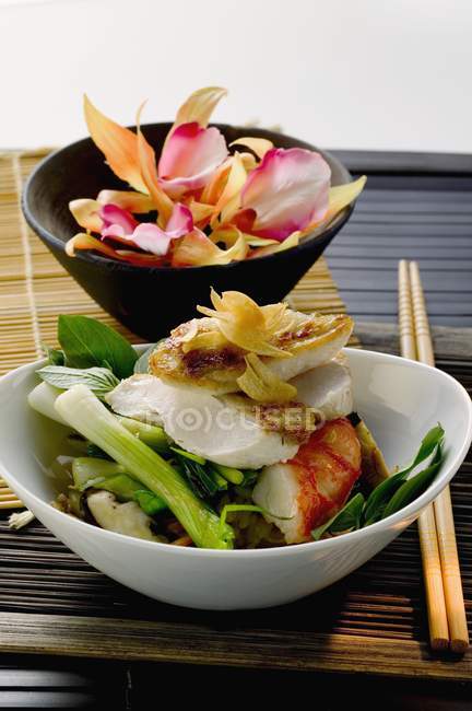 Chicken breast and shrimp on vegetables on white plate and black one — Stock Photo