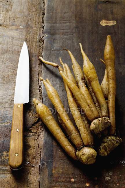 Raíces Krachai con cuchillo en superficie de madera - foto de stock