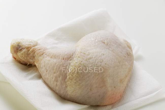 Jambe de poulet crue sur une serviette en papier — Photo de stock