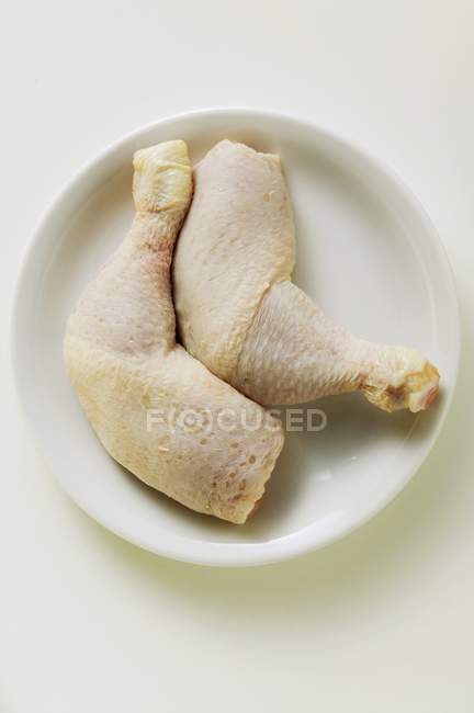 Jambes de poulet crues sur assiette — Photo de stock
