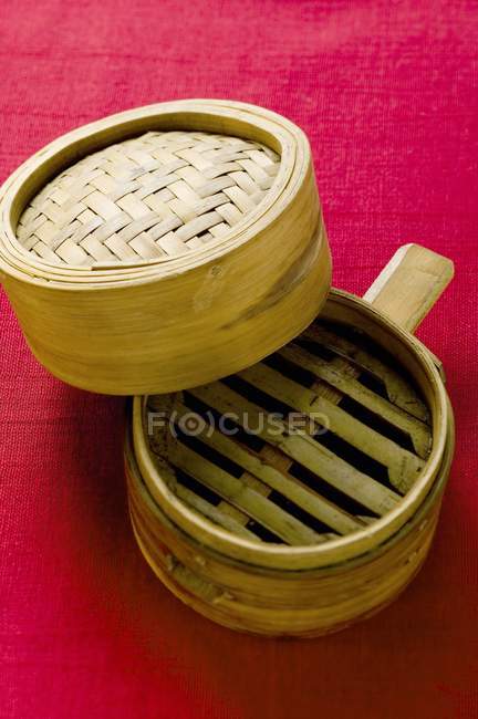 Vista de primer plano del vapor de bambú abierto sobre tela roja - foto de stock