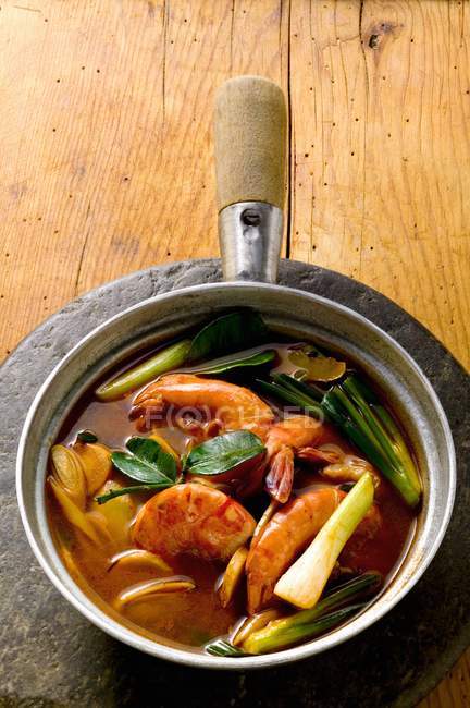 Shrimp soup with spring onions over wooden surface — Stock Photo