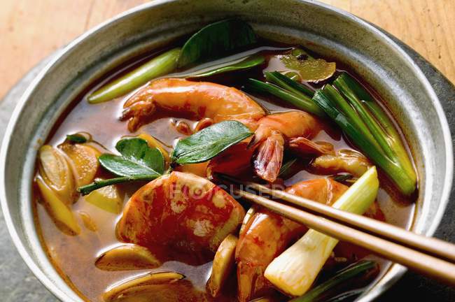 Shrimp soup with spring onions in black bowl with wooden sticks — Stock Photo