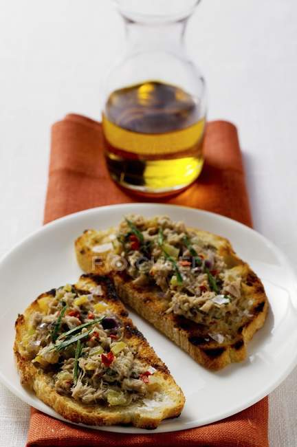 Closeup view of tuna Bruschetta on plate and carafe of oil — Stock Photo