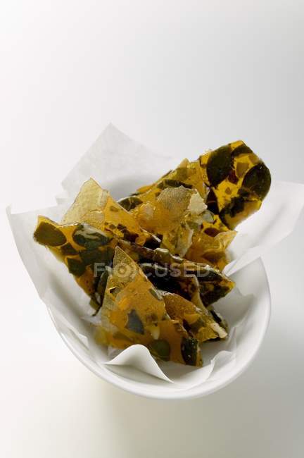 Closeup view of candied pumpkin seeds with paper in bowl — Stock Photo