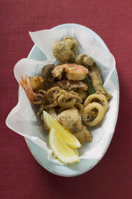 Closeup top view of deep-fried seafood on paper and oval plate — Stock Photo