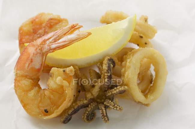 Vue rapprochée des crevettes frites, poulpe, anneaux calamars et citron — Photo de stock