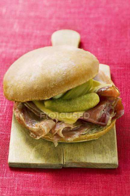 Bread roll with raw ham and gherkins — Stock Photo