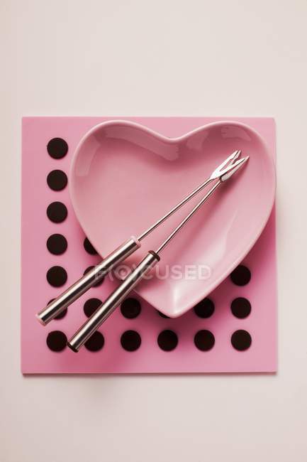 Top view of heart-shaped bowl with fondue forks — Stock Photo