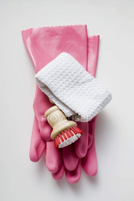 Vista superior de cerca de guantes de goma rosa, cepillo y toalla - foto de stock