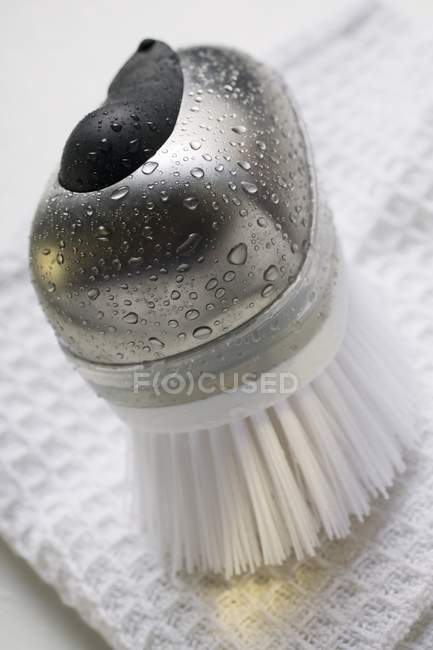 Vista close-up de escova com gotas de água e toalha de chá — Fotografia de Stock