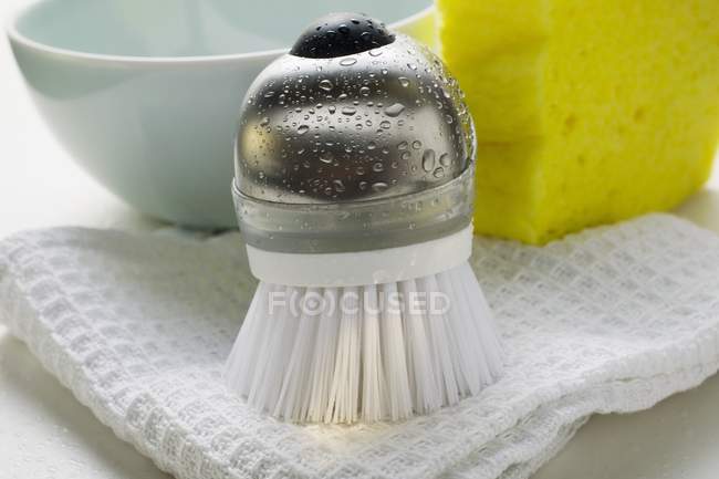 Vista de primer plano del cepillo con gotas de agua, toalla de té y esponja - foto de stock