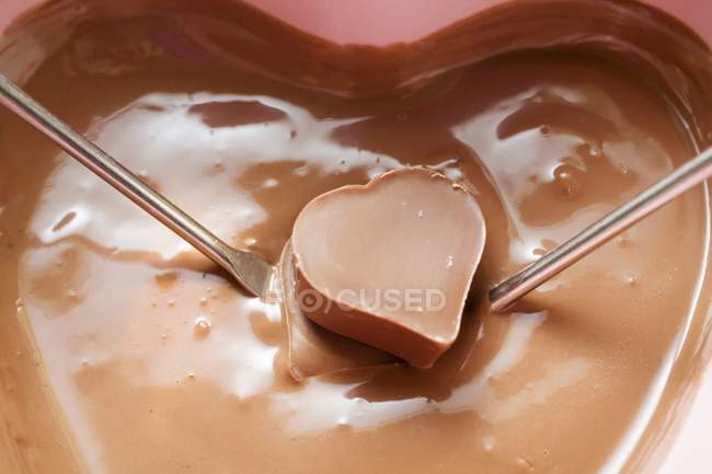 Fondue de chocolate con chocolate en forma de corazón - foto de stock