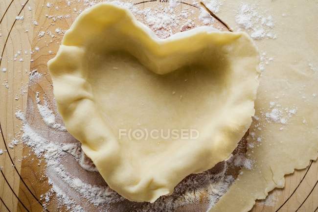 Closeup view of raw pastry in heart-shaped pie dish — Stock Photo