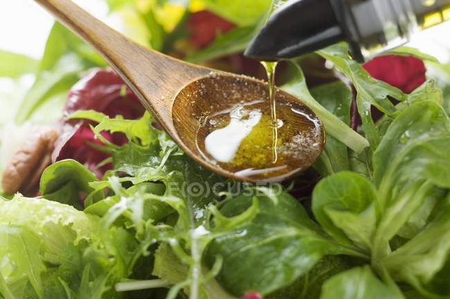 Pouring olive oil into salad — Stock Photo