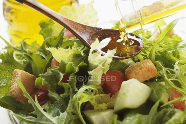 Versando olio d'oliva nell'insalata — Foto stock