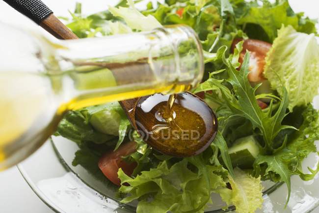 Verter aceite de oliva en ensalada - foto de stock