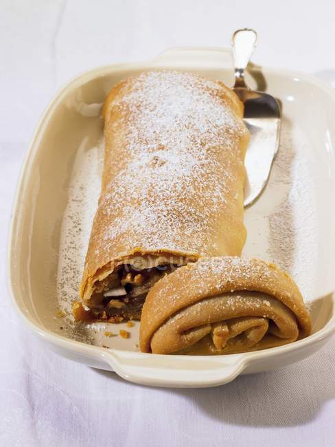 Closeup view of cut fruit strudel with nuts and icing sugar — Stock Photo