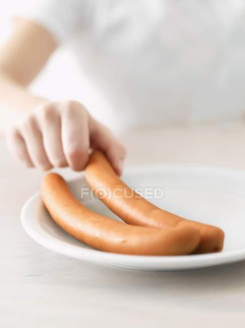 La main d'un enfant cherchant une frankfurter — Photo de stock