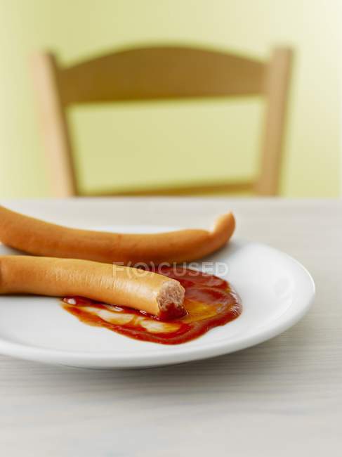 Франкфуртеры с кетчупом на тарелке — стоковое фото