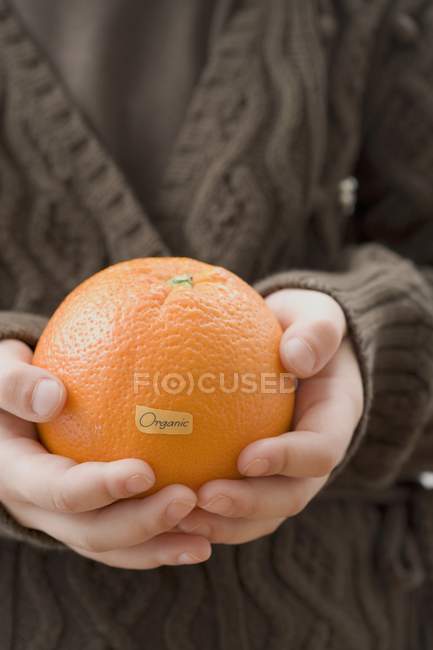 Girl holding organic orange — Stock Photo