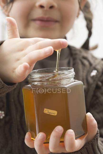 Girl tasting honey — Stock Photo