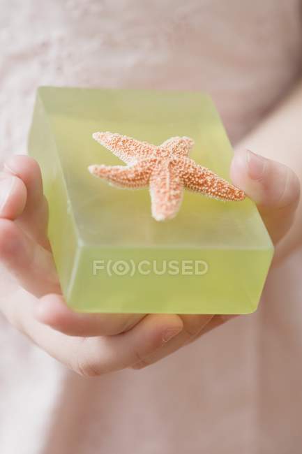 Vue rapprochée de fille tenant savon vert avec étoile de mer — Photo de stock