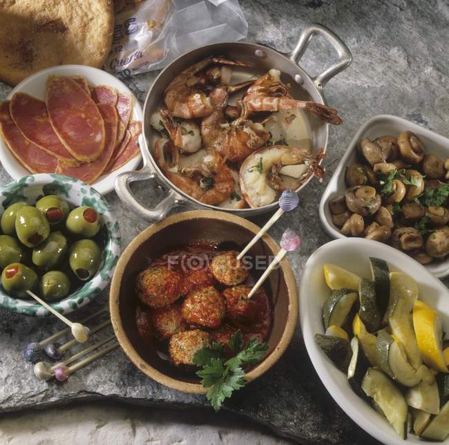 Vista elevada de una variedad de aperitivos españoles con carne, mariscos, setas y verduras - foto de stock